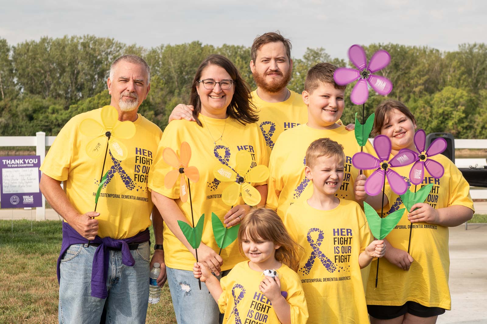 Family wearing yellow shirts with Her Fight is Our Fight message holding flowers at the Walk to End Alzheimer’s in St. Joseph, Missouri.