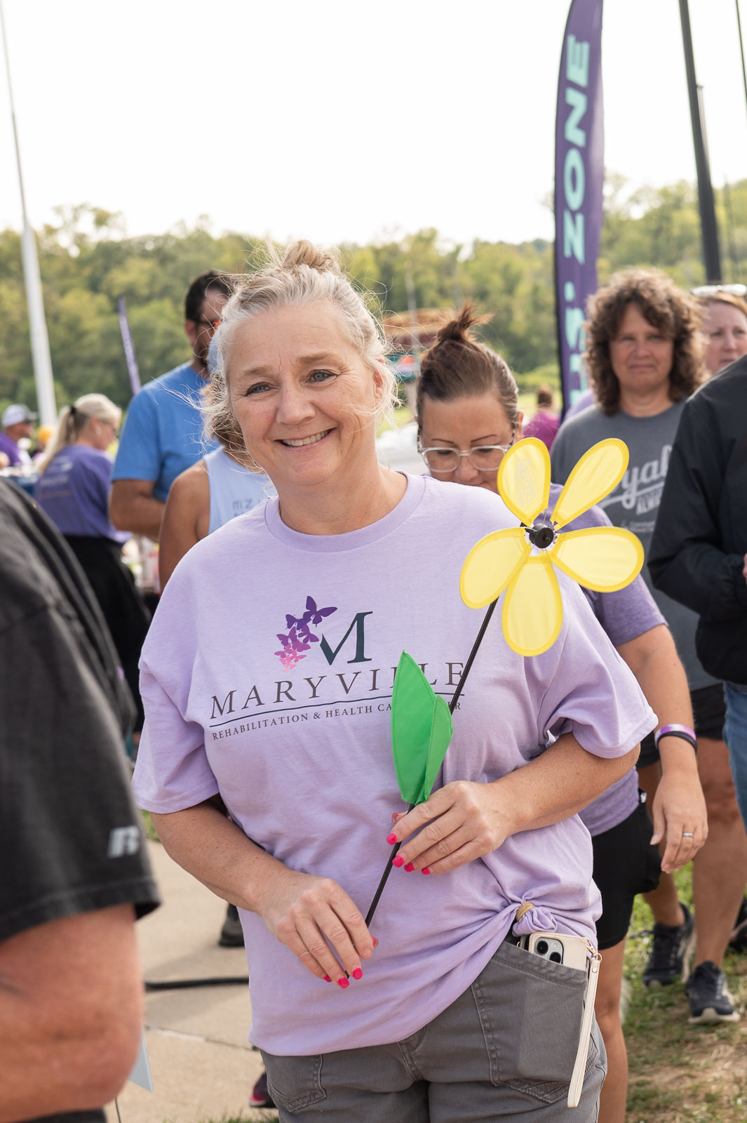 Smiling woman wearing Maryville shirt and holding a yellow flower at the Walk to End Alzheimer’s in St. Joseph, Missouri.