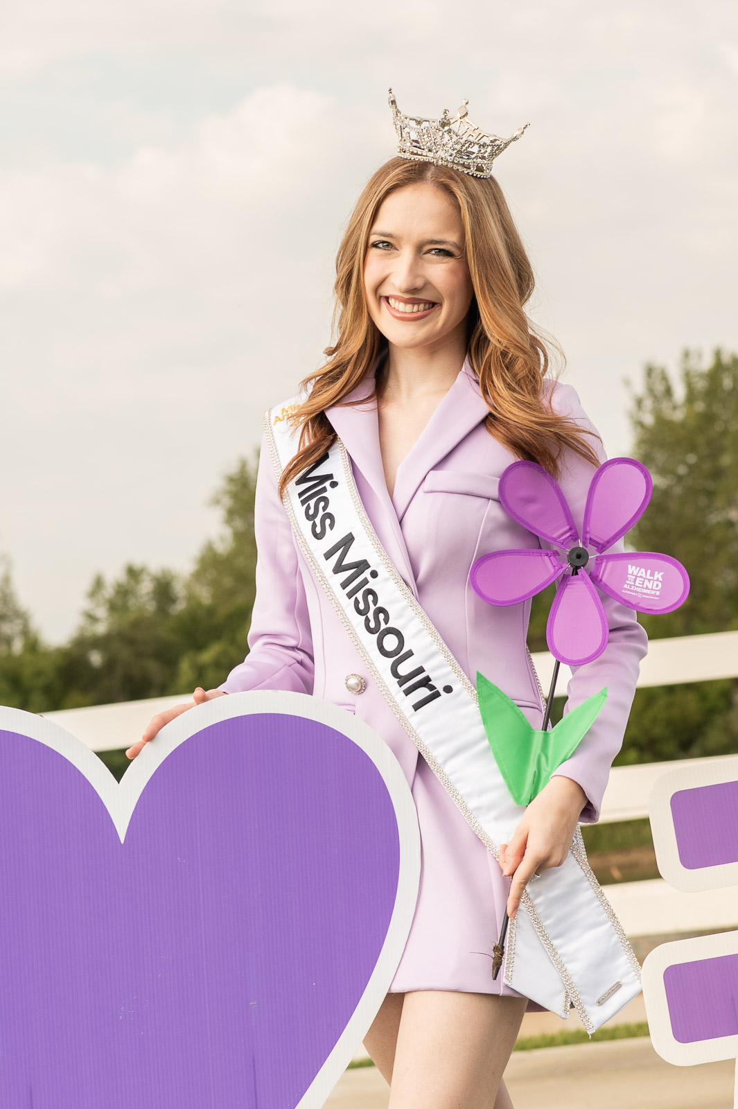 Miss Missouri smiling and holding a purple flower at the Walk to End Alzheimer’s in St. Joseph, Missouri.