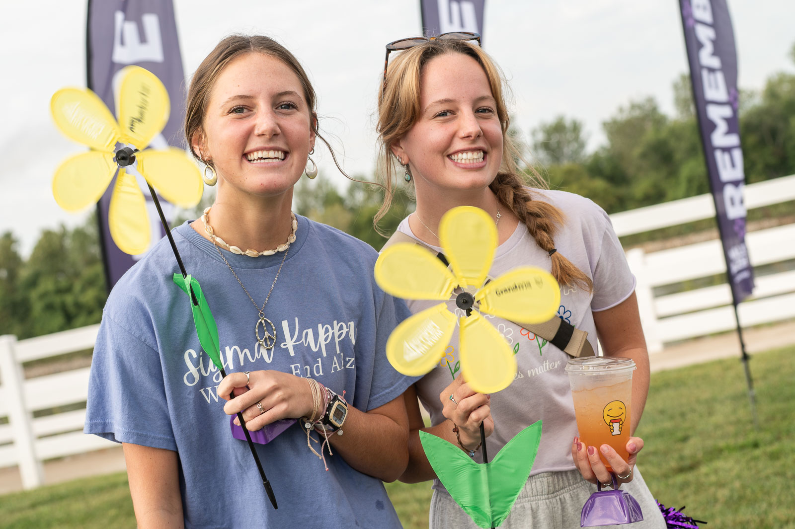 Two smiling participants holding yellow flowers at the Walk to End Alzheimer’s in St. Joseph, Missouri.