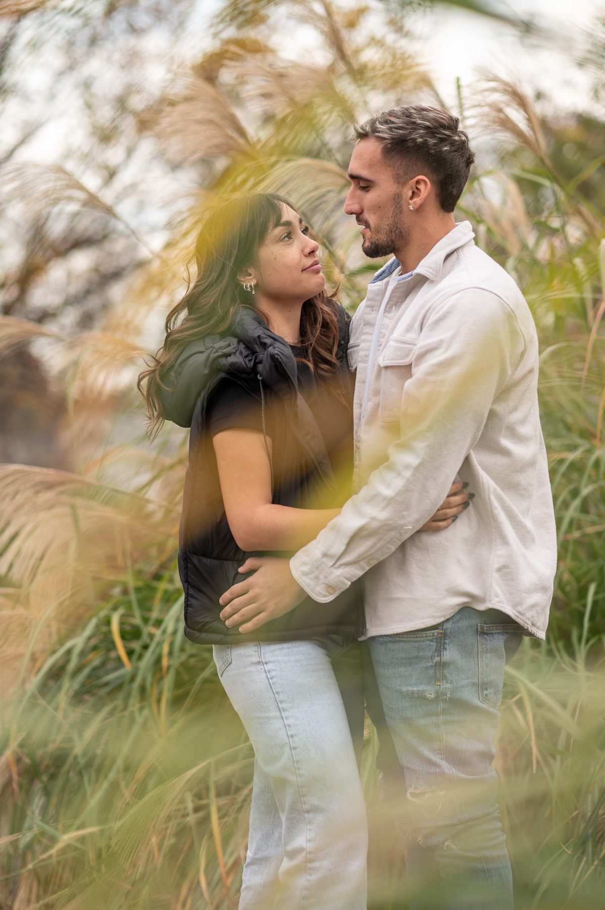 Young couple posing during a fall photo session in St. Joseph, Missouri surrounded by autumn grass.
